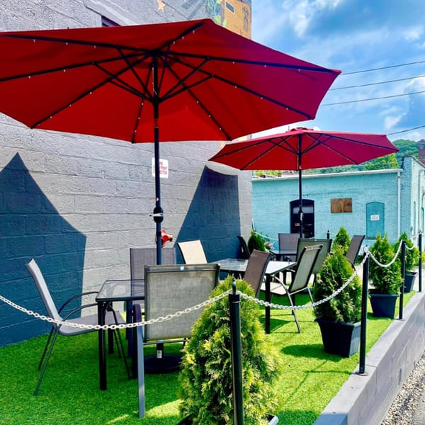 Outdoor patio at Runaway Train Brewery with red umbrellas, tables, chairs, and potted greenery.