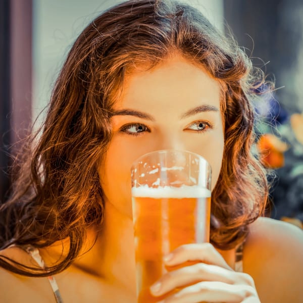 A young woman with long brown hair sips a glass of beer at Runaway Train Brewery.