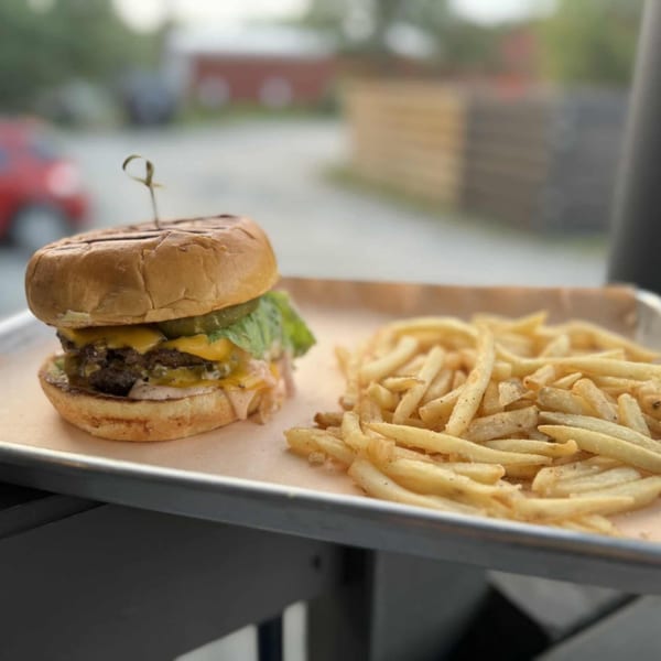 Runaway Train Brewery's double cheeseburger with lettuce, pickles, and fries on a metal tray.