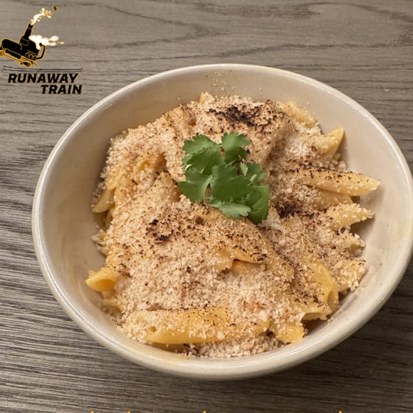 A bowl of Runaway Train Brewery's macaroni and cheese, topped with breadcrumbs and a sprig of cilantro.