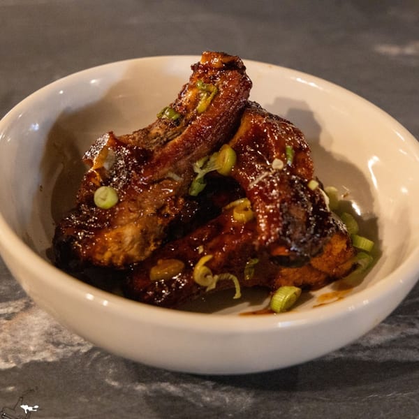 Runaway Train Brewery's sticky, glazed ribs with green onion garnish in a white bowl.